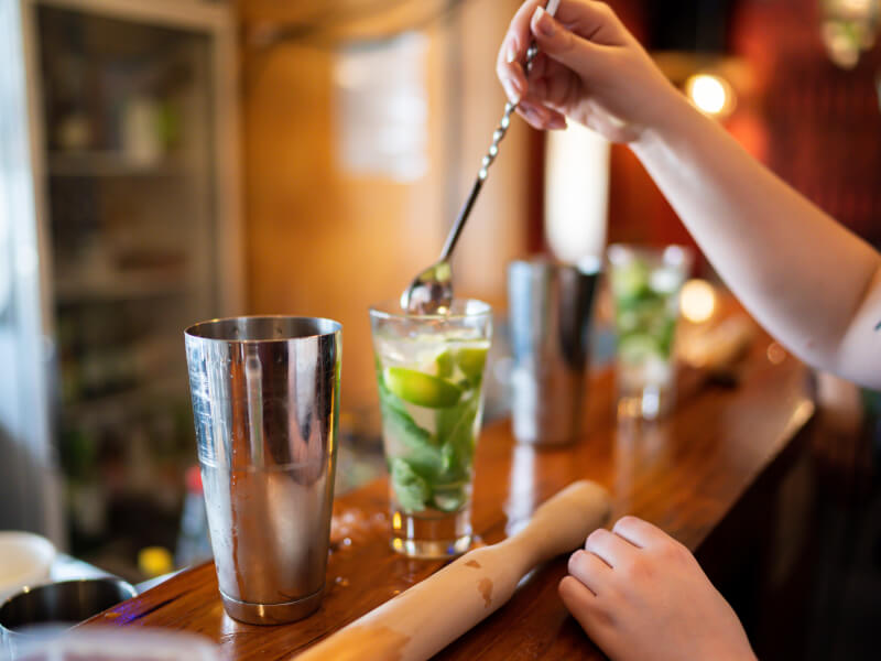 Person muddling a mojito at a cocktail class in Manchester